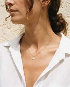 Cuello con un collar fino dorado y una camisa blanca
